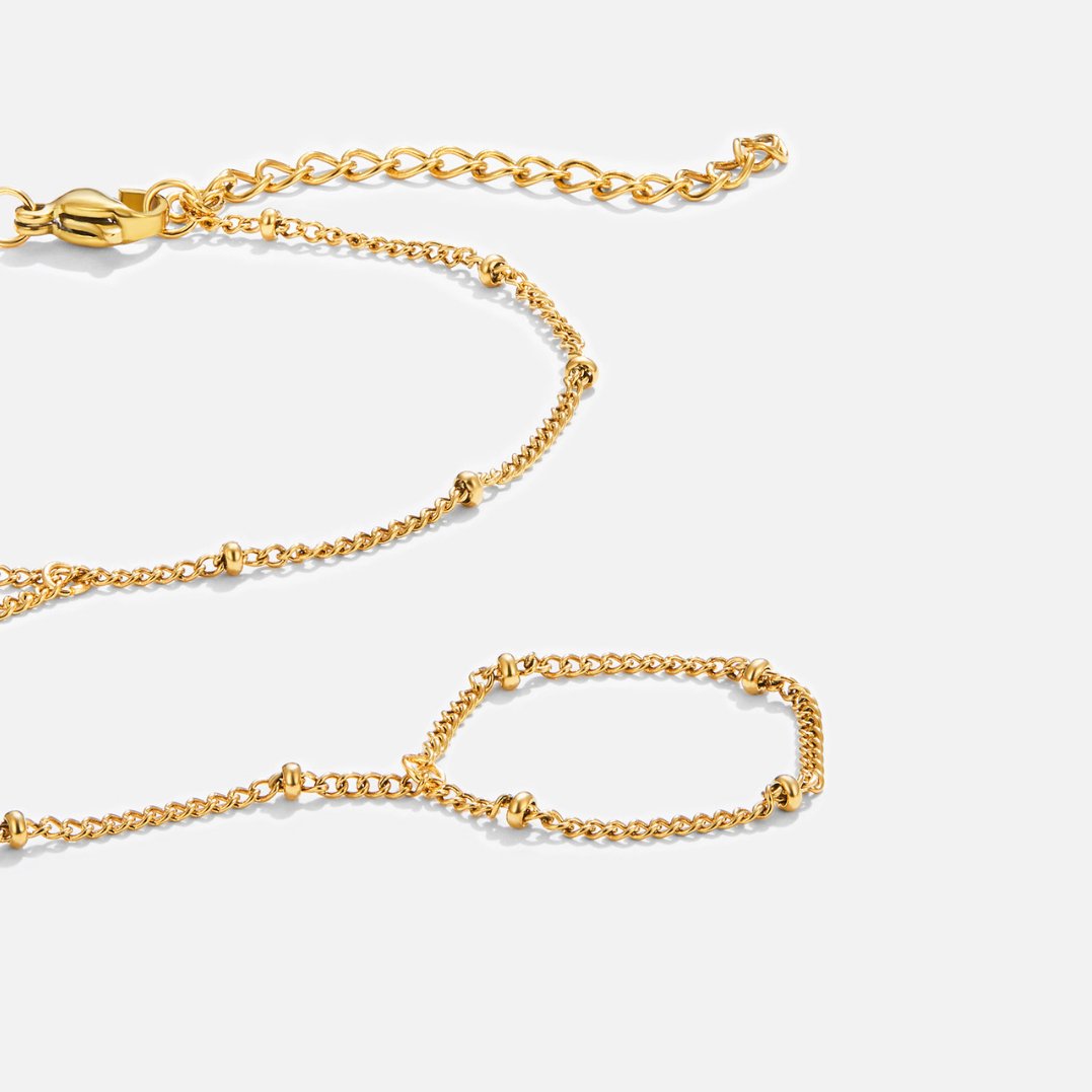Free 18K Gold Hand Chain Bracelet, flat-lay of gold chain with beaded links and lobster clasp