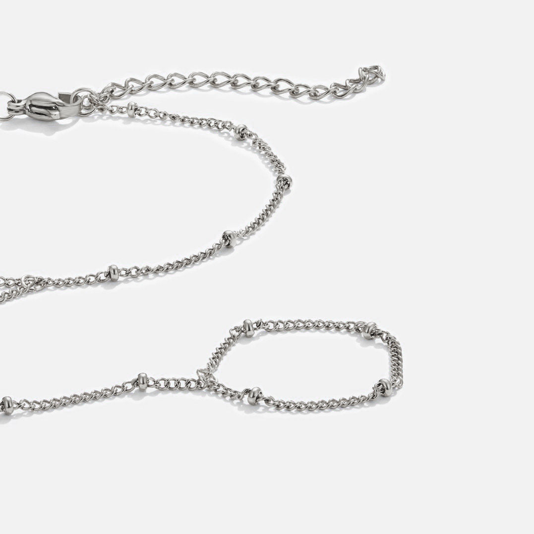 Silver Hand Chain Bracelet, flat lay of a silver chain with beaded links and a ring loop, on white