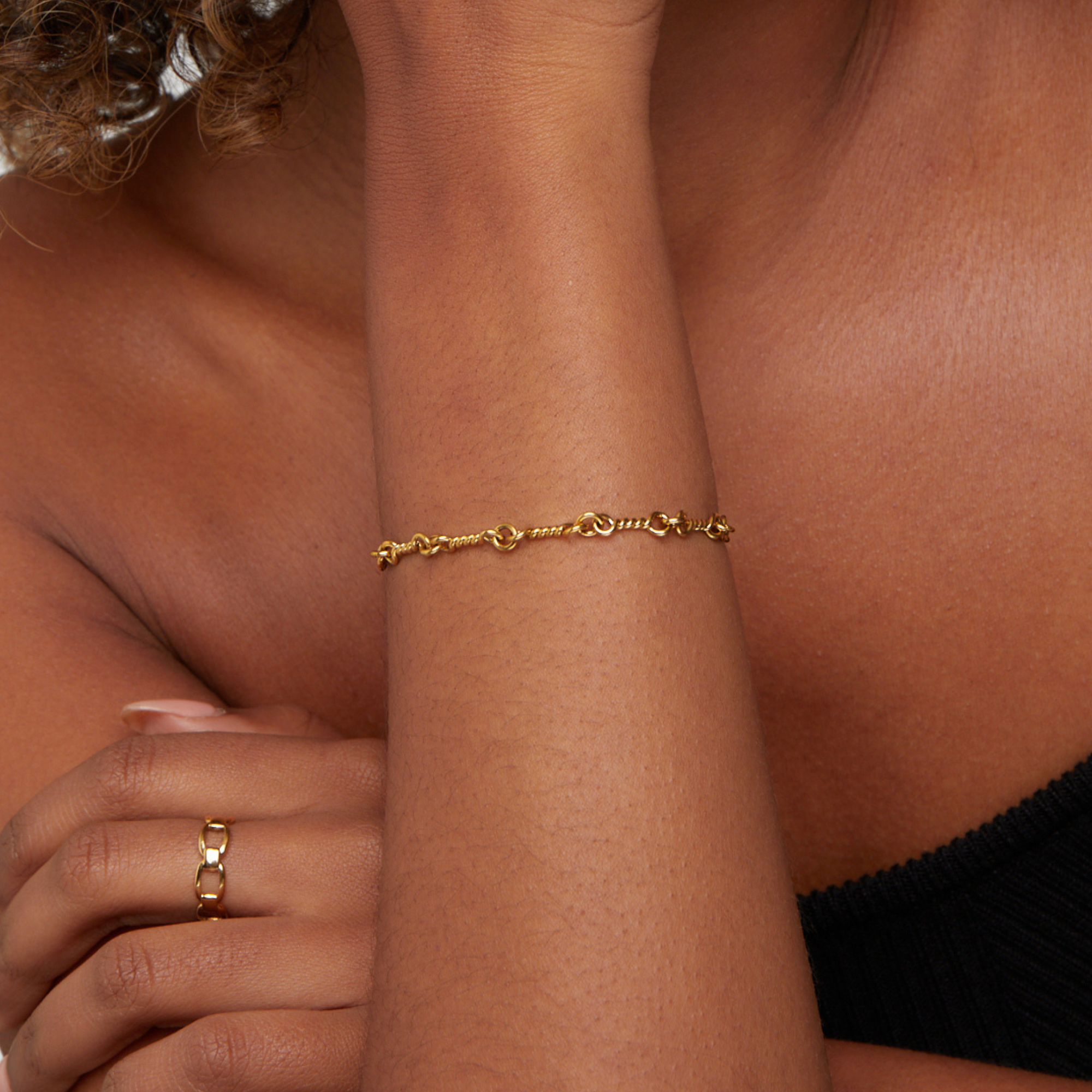 Figaro Gold Knot Chain Bracelet, worn on a wrist with a gold chain ring on a finger