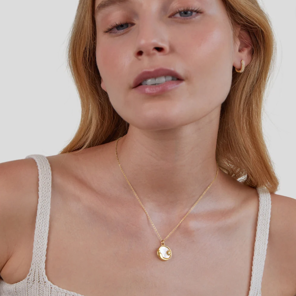 'Dreaming in the Clouds' Moon & Star Necklace, worn on a model with a gold hoop earring and