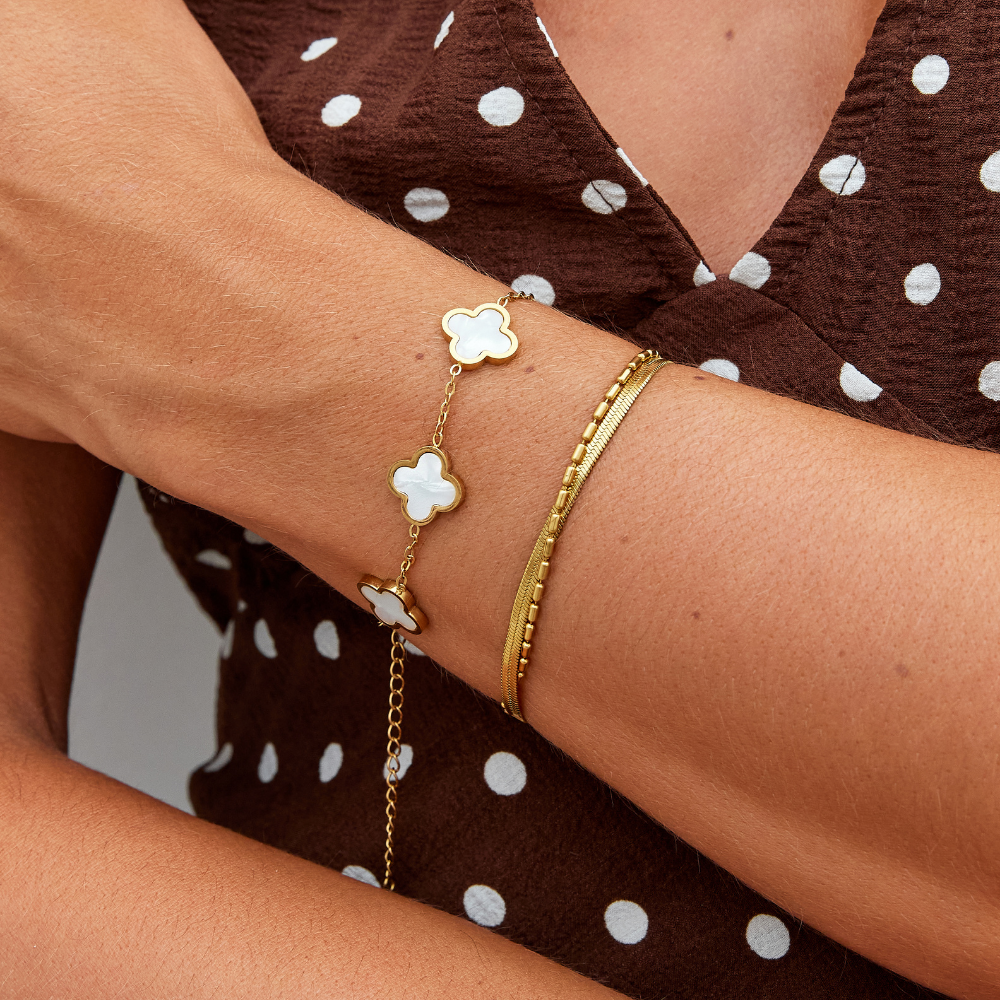 White Clover Bracelet, worn on a wrist with a gold snake chain bracelet