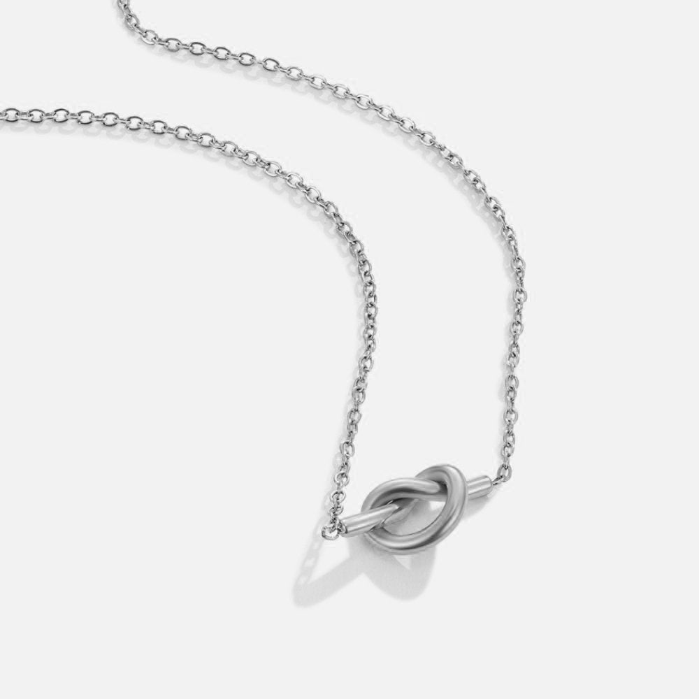 Adela Knot Silver Necklace, silver chain necklace with a knot pendant, laid flat on white