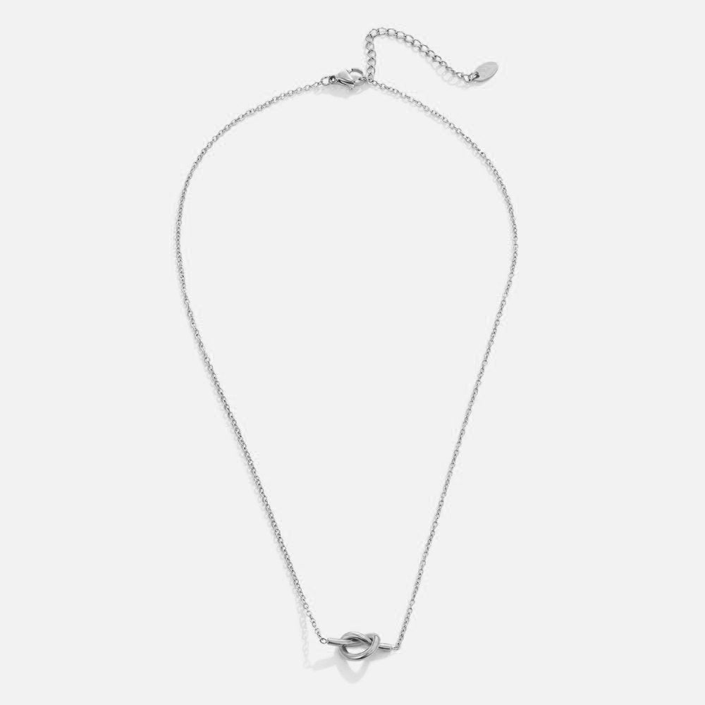 Adela Knot Silver Necklace, laid flat on a pale background, silver chain with a knot pendant