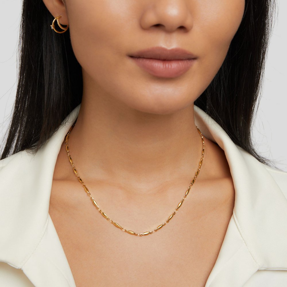 Alea Chain Necklace, worn on a neck with a gold hoop earring and white collar