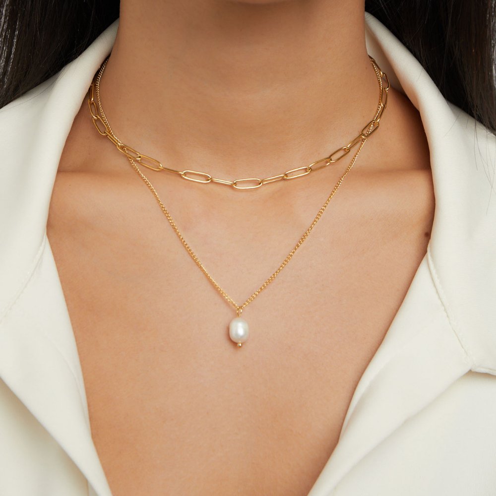 Angela Pearl Gold Necklace, worn on a neck with white collared top, layered gold chains and