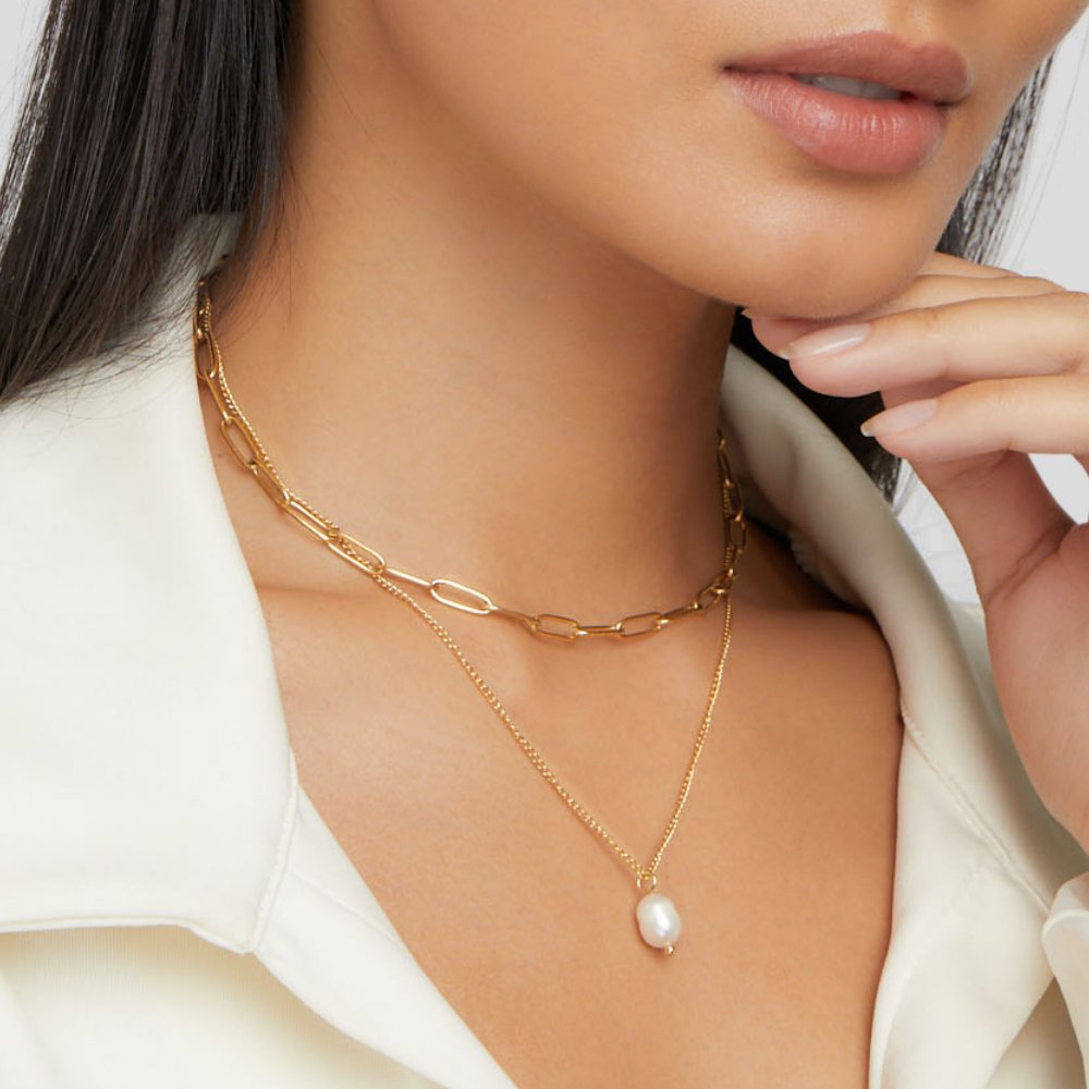 Angela Pearl Gold Necklace, worn on a neck layered with chunky gold chain and a pearl pendant