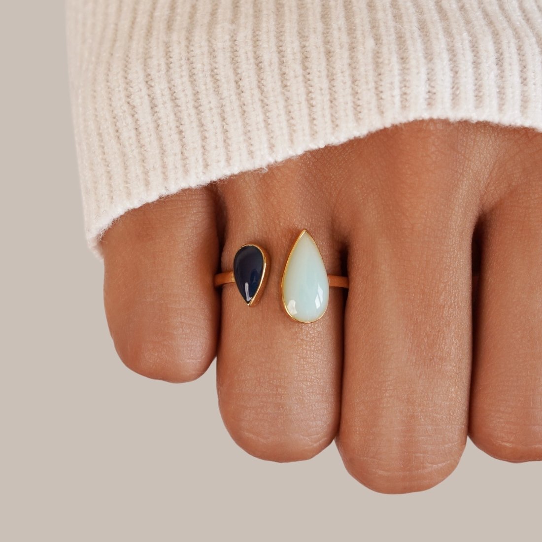 Aquamarine Teardrop Ring, worn on a finger with a cream knit sleeve, dark and pale teardrop stones