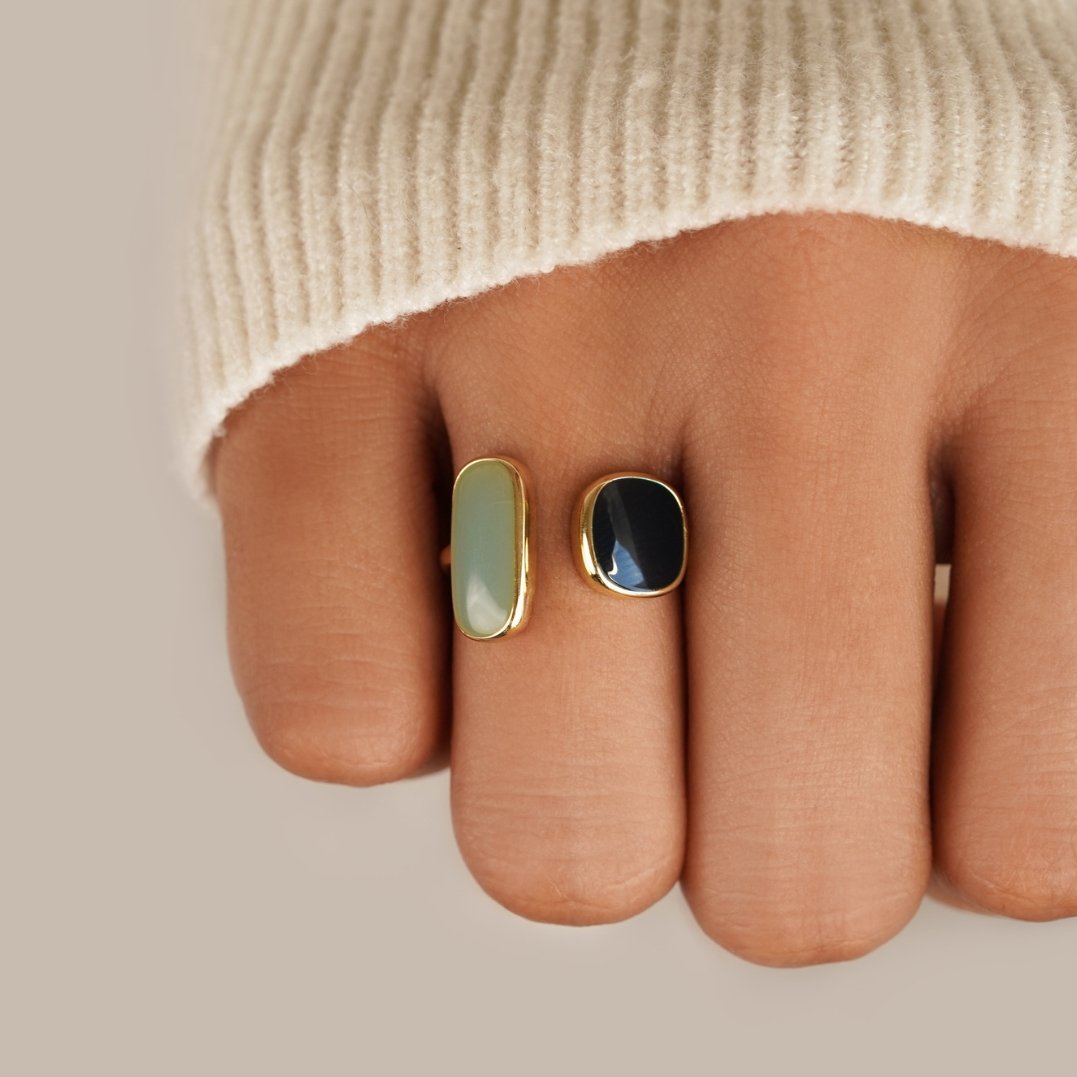 Aquamarine Wrap Ring, worn on a finger in a cream knit sleeve, pale green and black stones