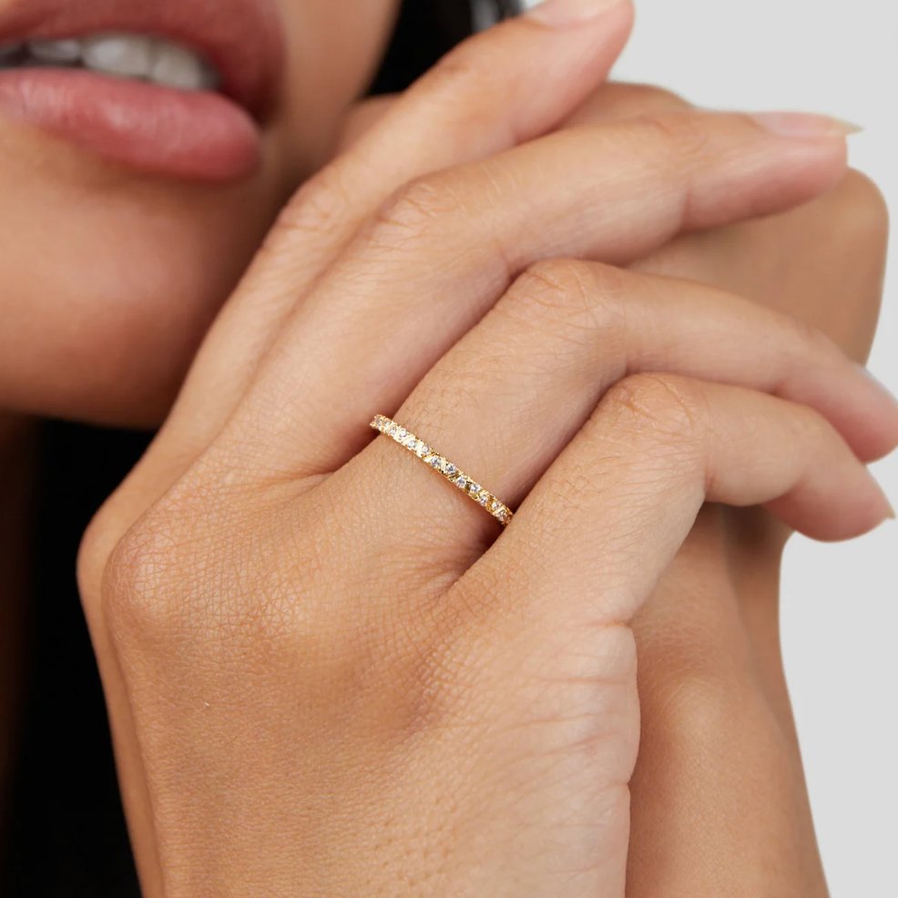 Arquette Gold & Crystal Band Ring, worn on a hand near lips, close-up of pavé stones