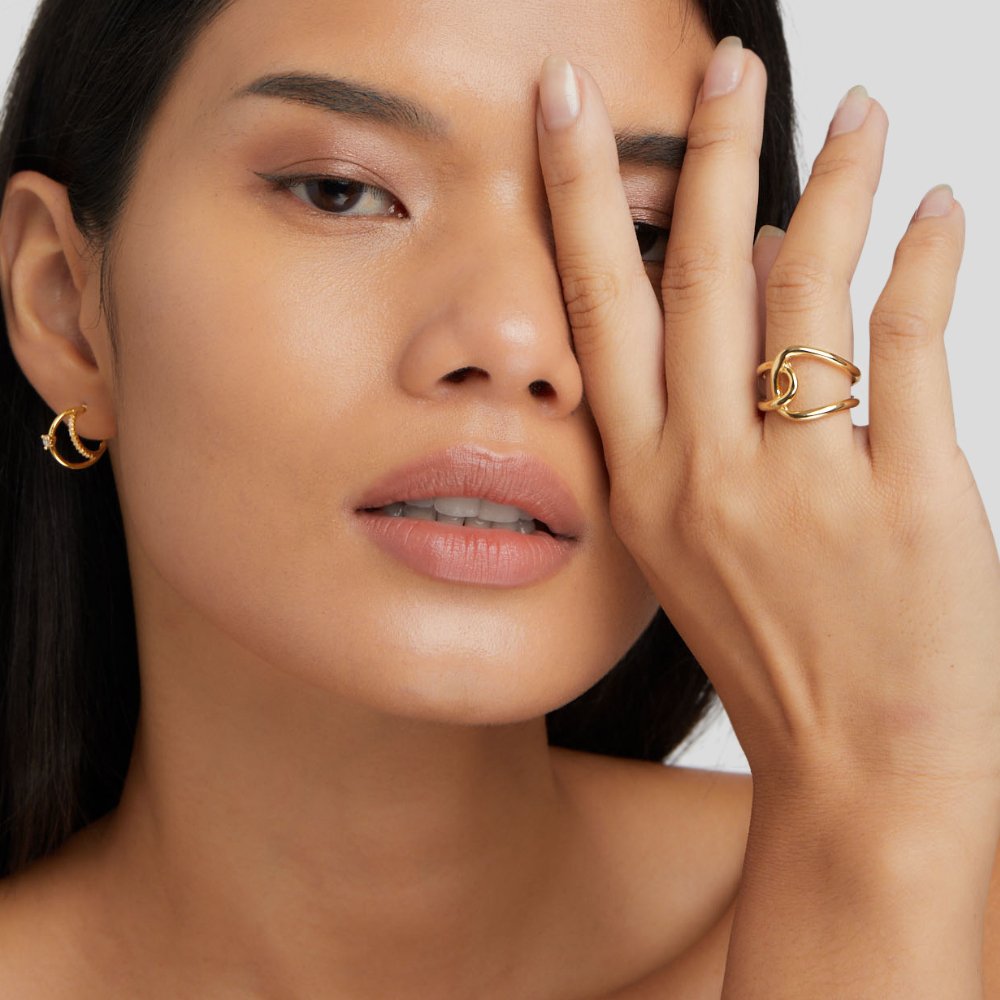 Astrid Gold Ring, worn on a hand covering one eye, gold ring on index finger