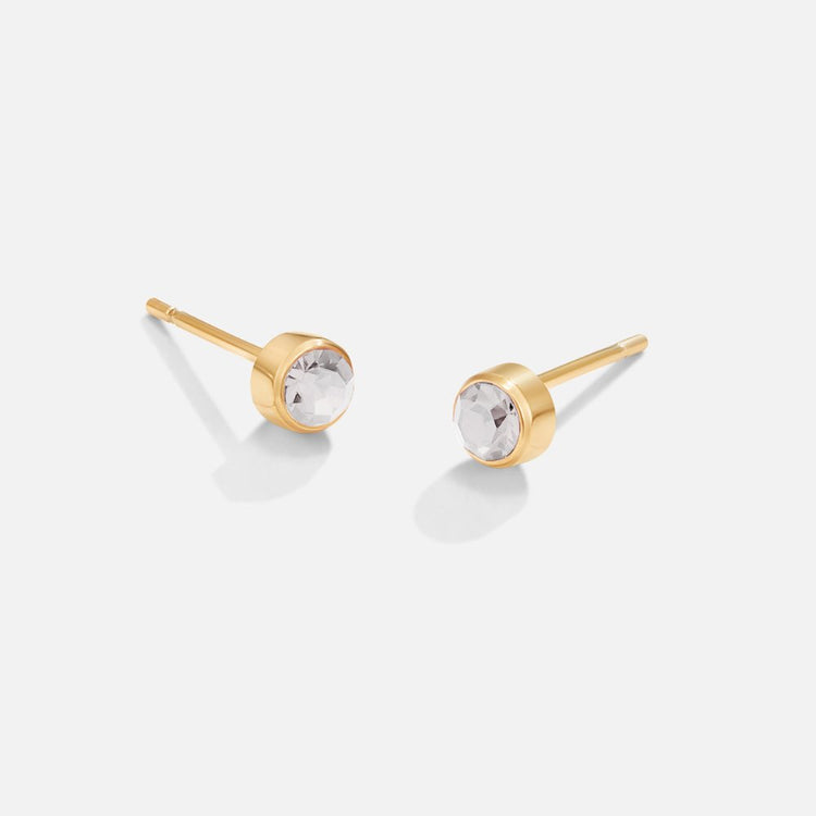 Birthstone Stud Earrings, pair of gold stud earrings with clear round stones, on a plain background