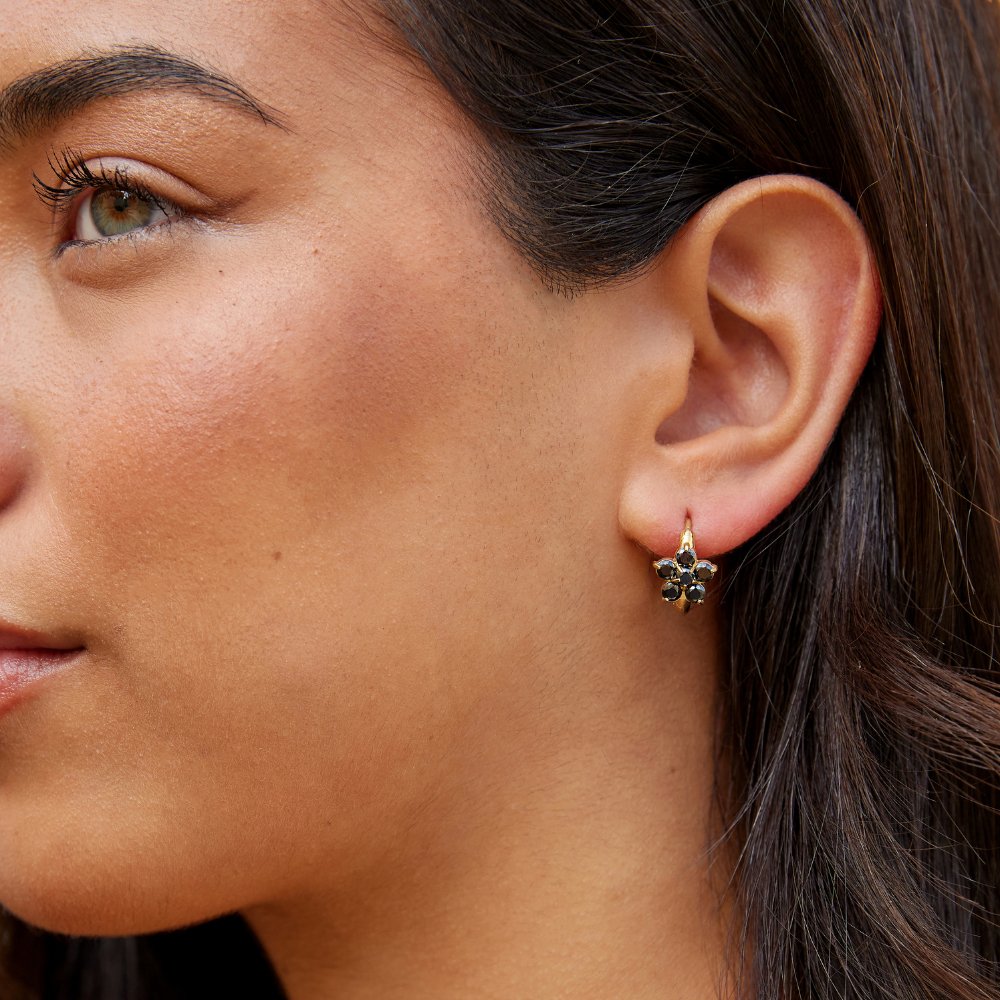 Black Crystal Flower Hoop Earrings, worn on an ear, close-up with dark stones in a flower cluster