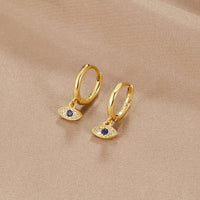 Blue Evil Eye Drop Earrings, pair of gold hoop earrings on beige fabric, evil eye charms with
