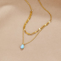Blue Opal Teardrop Layered Necklace, two gold chains on beige satin, teardrop opal pendant