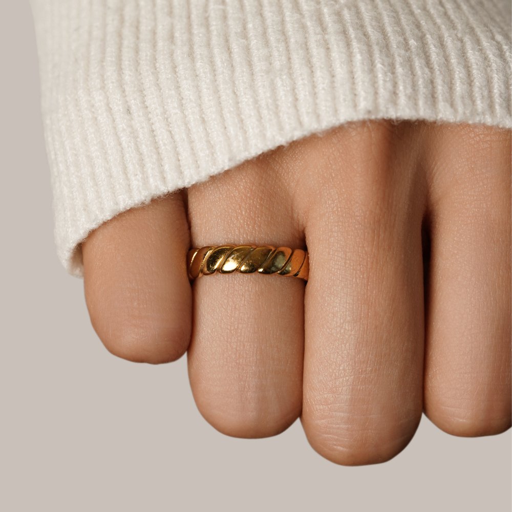 Calira Twisted Infinity Ring, worn on a hand with a cream knit sleeve, close-up on the finger