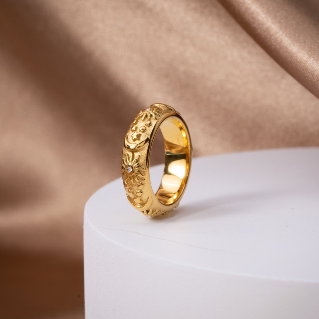 Celestial Gold Ring, standing upright on a white pedestal against tan satin