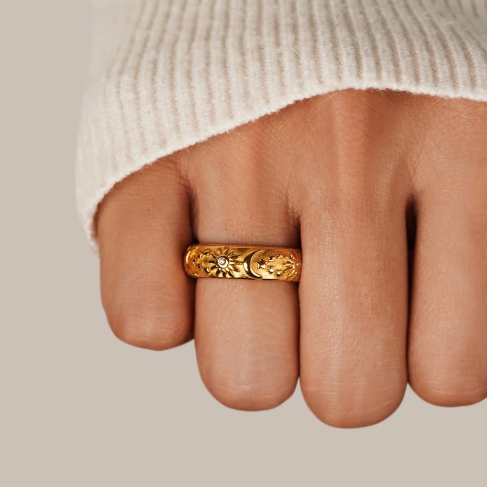 Celestial Gold Ring, worn on a hand in a cream knit sleeve, close-up of gold band