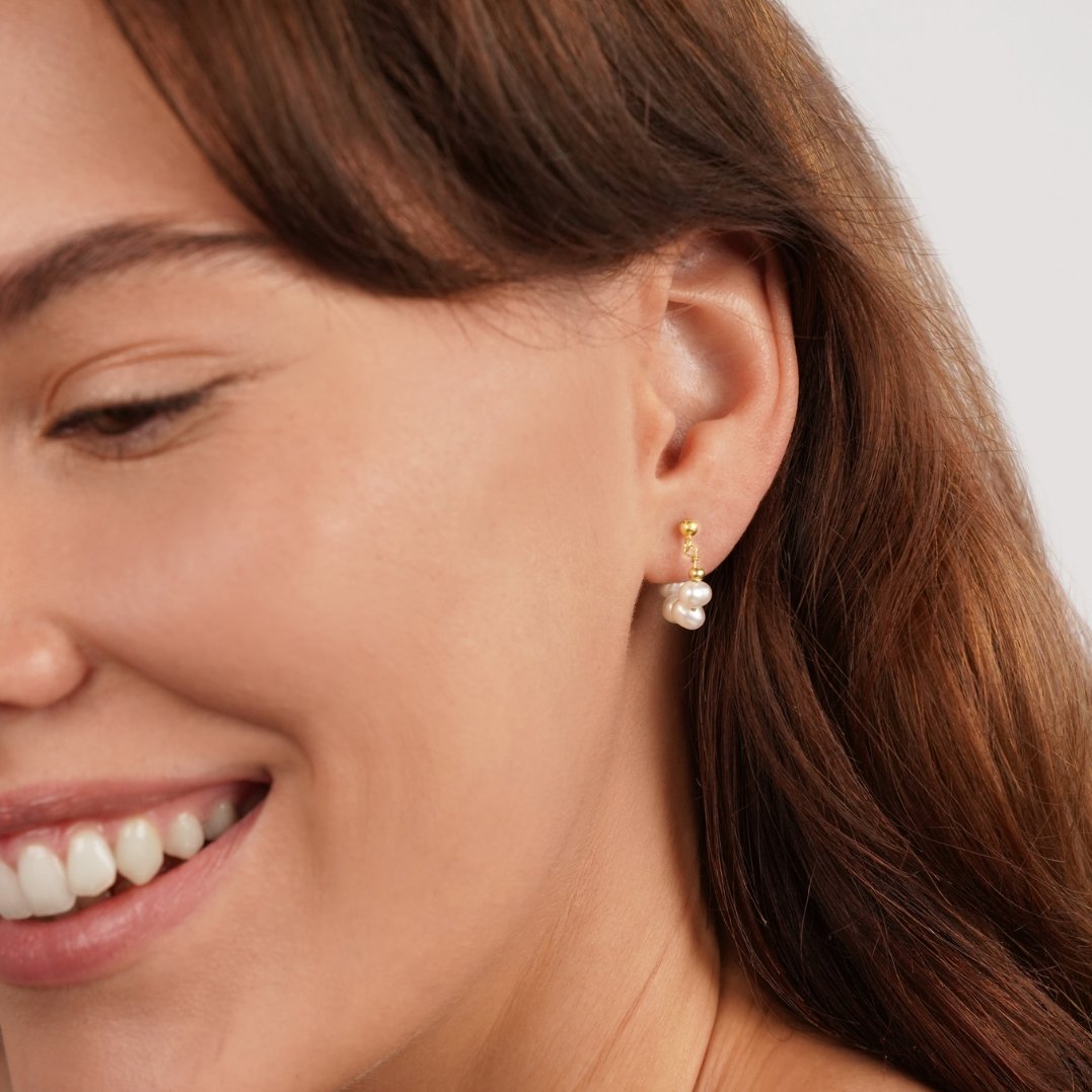 Celine Pearl Hoop Earrings, worn on an ear with a gold post and small pearl drop