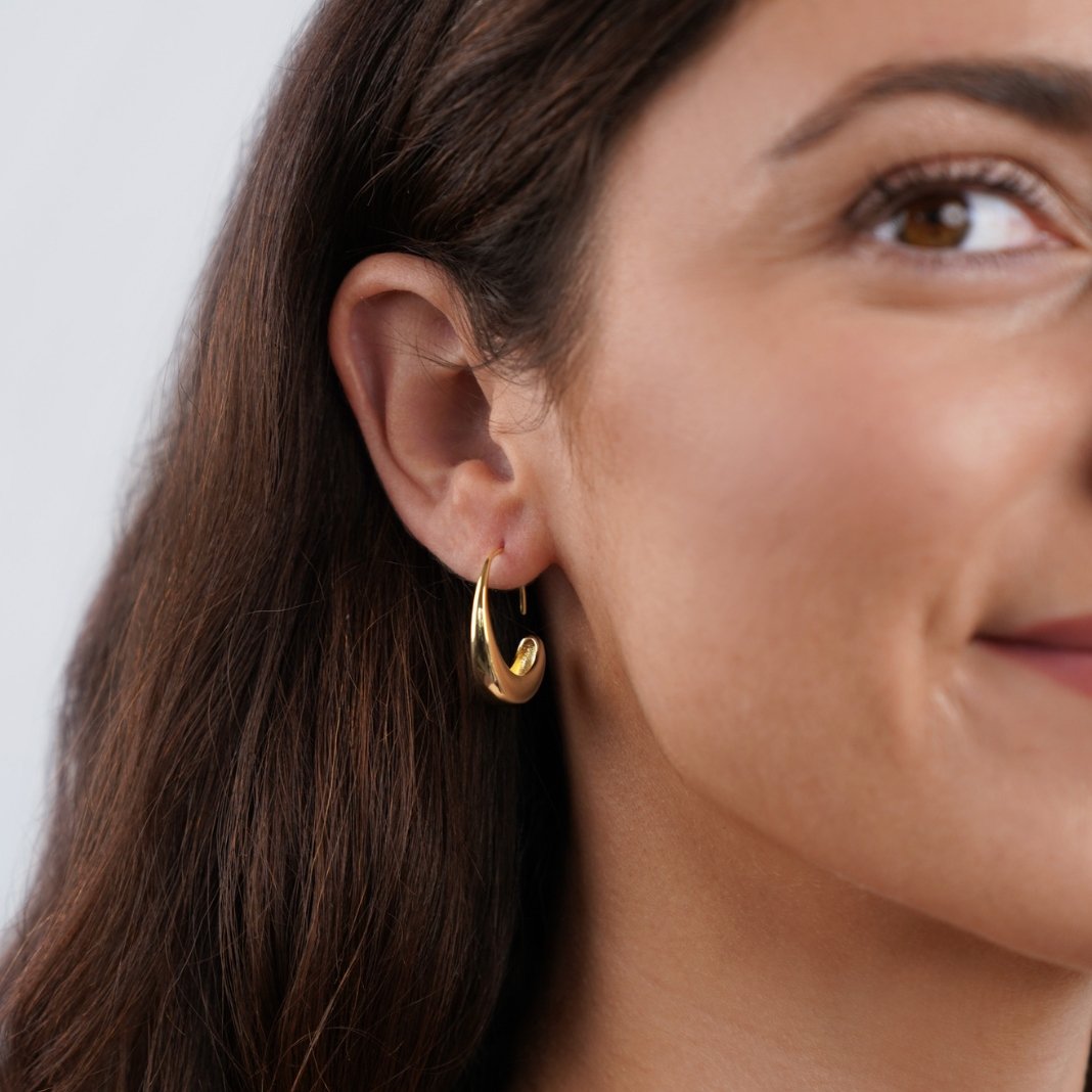 Classic Drop Hoop Earrings, worn on an ear, polished gold hoop with a teardrop curve