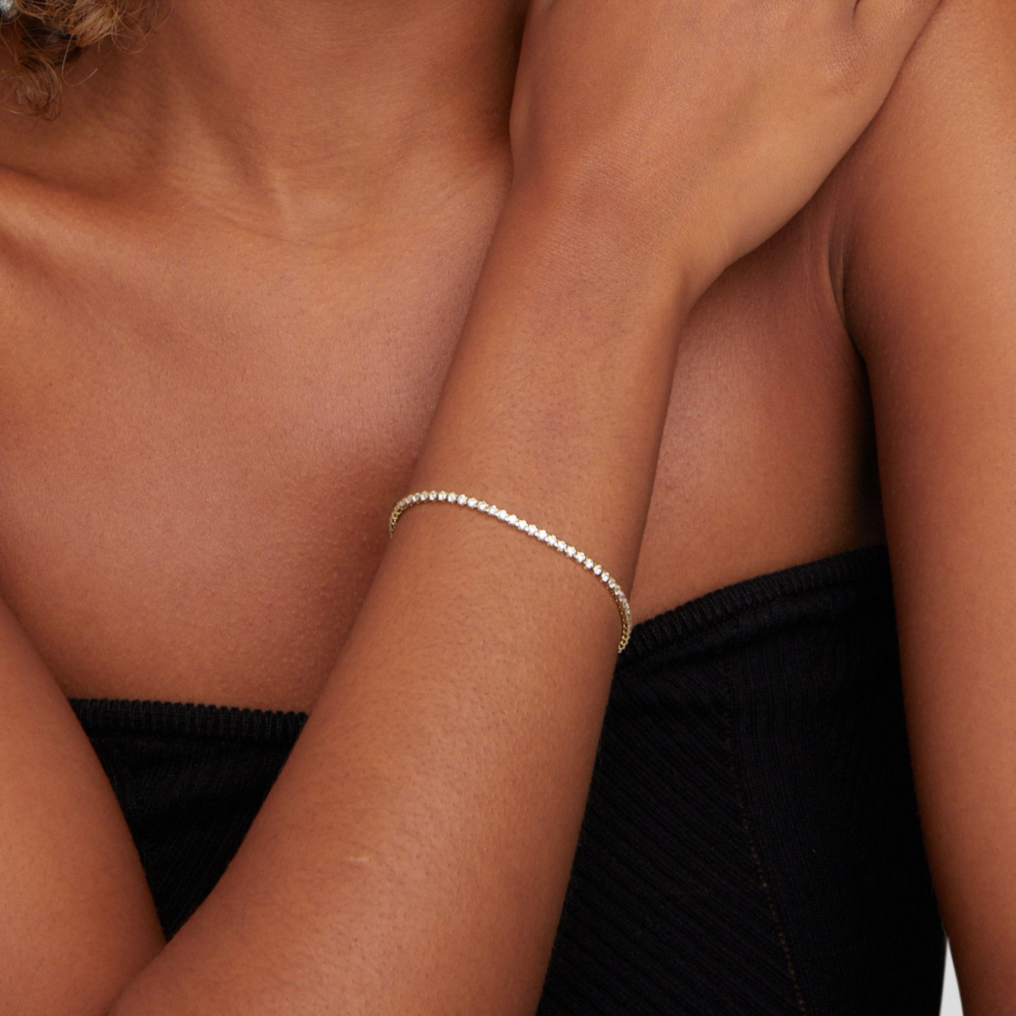Cordelia Gold Tennis Bracelet, worn on a wrist, against a black ribbed top