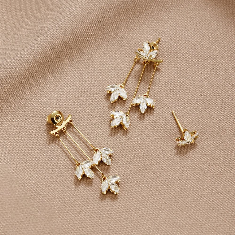 Crystal Lotus Waterfall Earrings, two gold drop earrings laid flat on beige satin, with