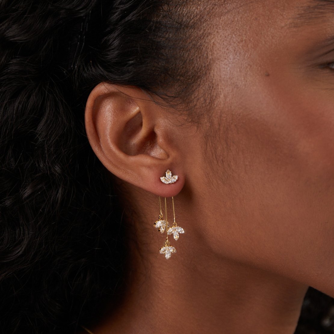 Crystal Lotus Waterfall Earrings, worn on an ear, close-up of gold drop earrings with crystal petals
