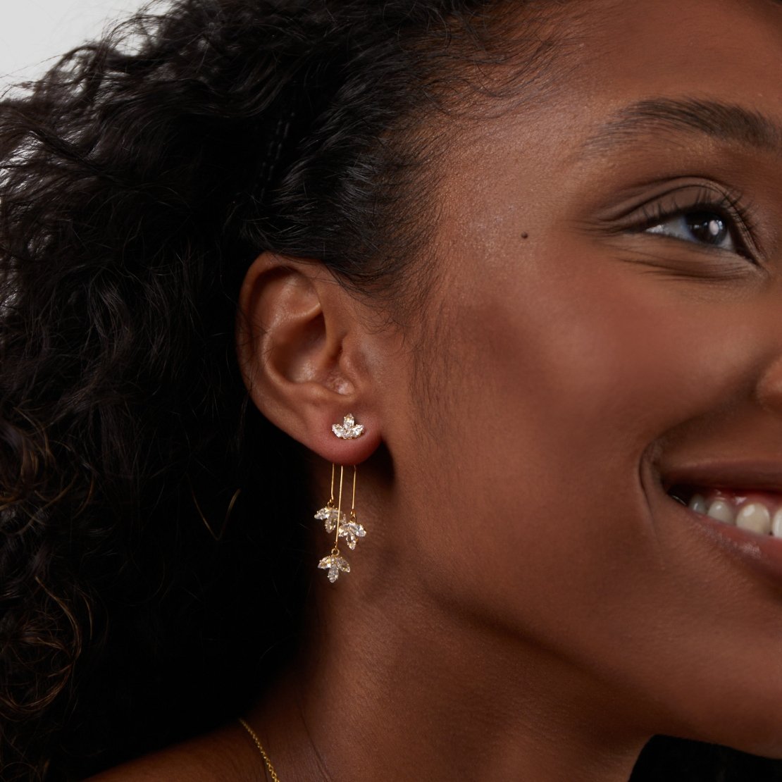 Crystal Lotus Waterfall Earrings, worn on an ear, gold with clear crystal flower studs and drops