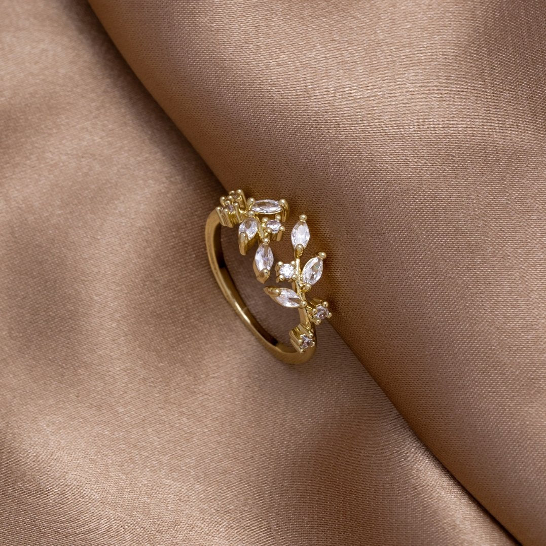 18K Gold Crystal Vine Ring, lying on draped tan satin, gold band with clear leaf-shaped stones