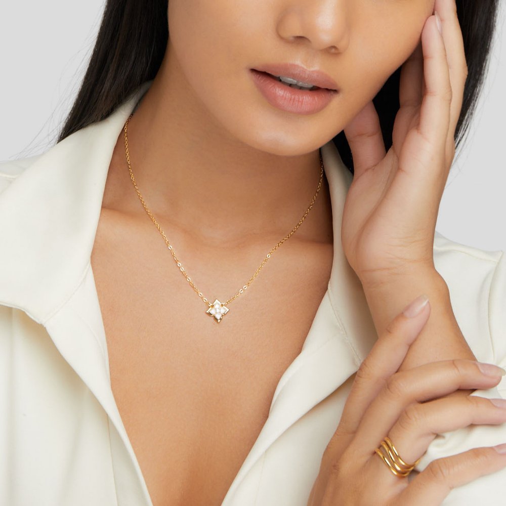 Dalia White Iris Clover Necklace, worn on a model in a white collared top, hand at her cheek