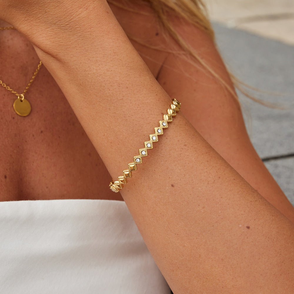 Elle Crystal Marquise Bangle, worn on a forearm with a gold disc necklace