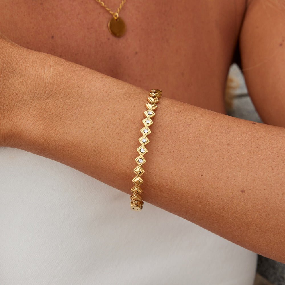 Elle Crystal Marquise Bangle, worn on a wrist with a gold coin necklace, close-up