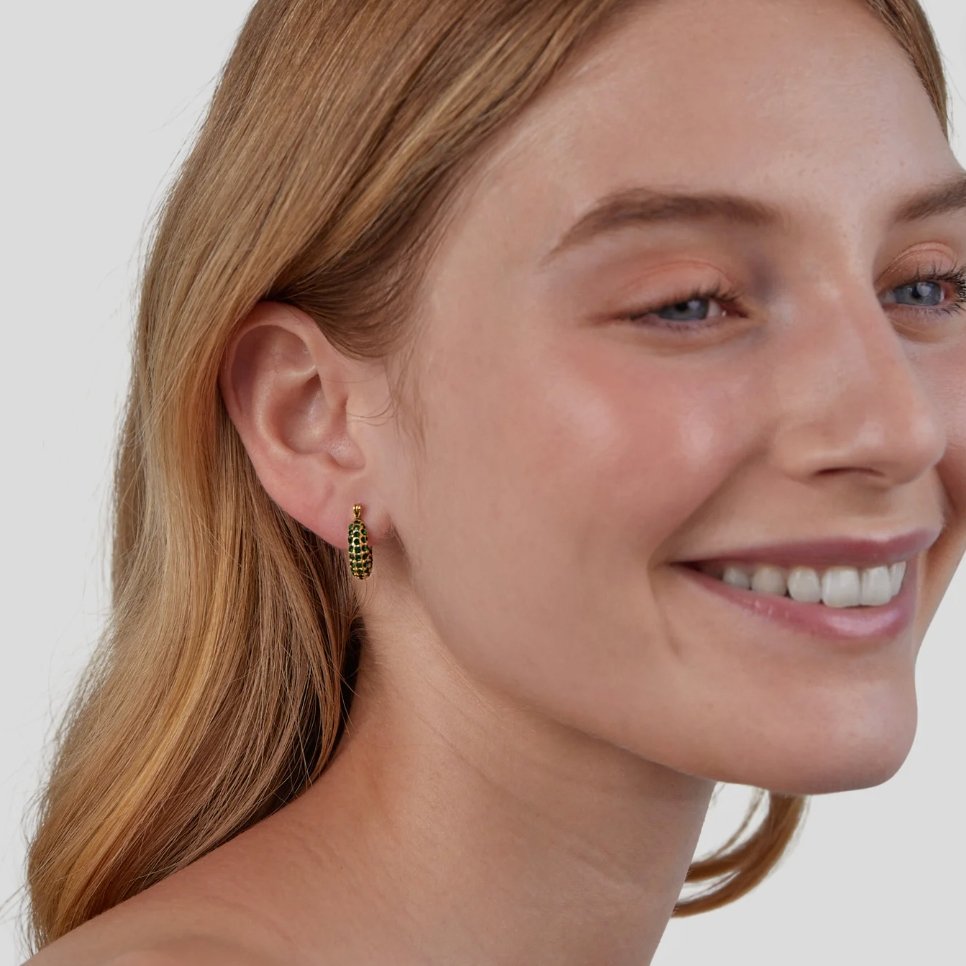 Emerald Beauty Hoop Earrings, worn on an ear of a smiling model, green stones in gold