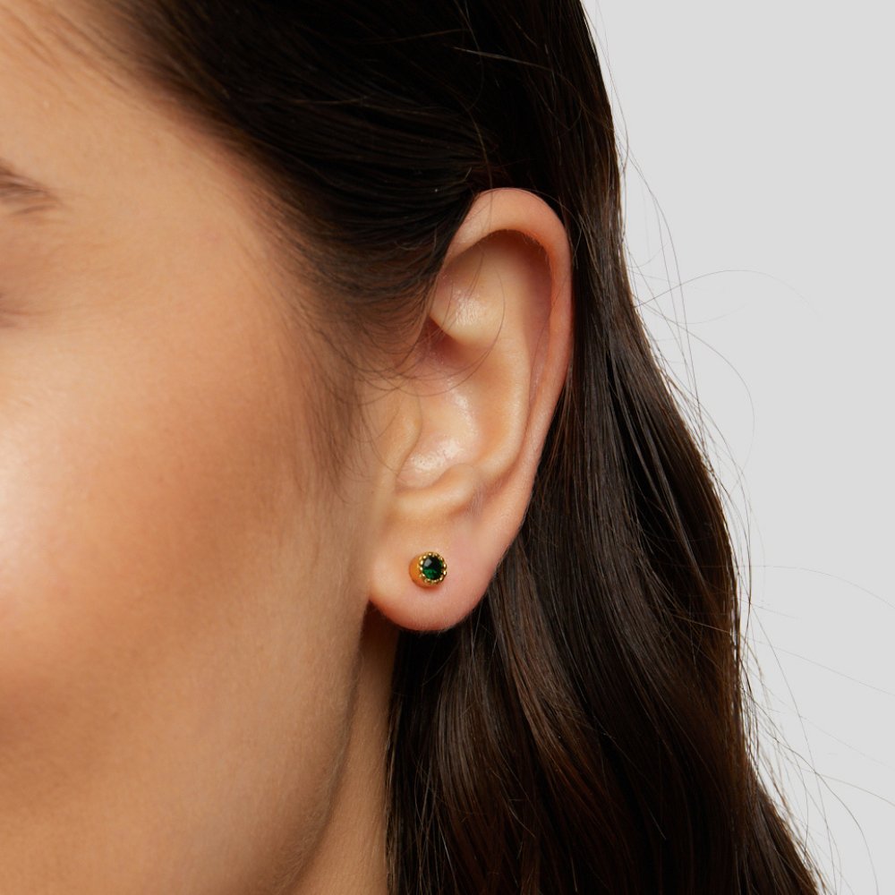 Emerald Green Stud Earrings, worn on an ear, small gold stud with a green stone