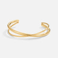 Eva Gold Twist Bracelet, open cuff with two gold bands crossing on a white background