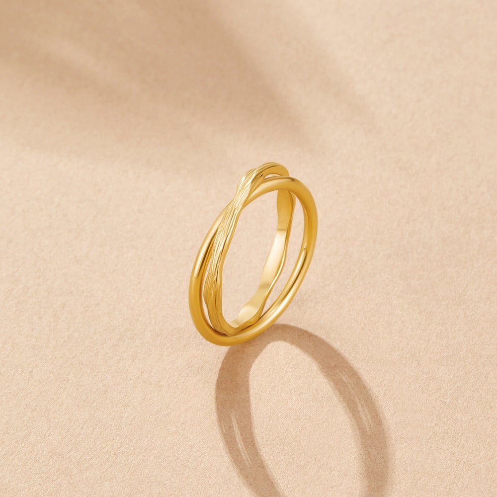 Forever Entwined Gold Ring, gold ring standing upright on a beige surface, textured twisted band