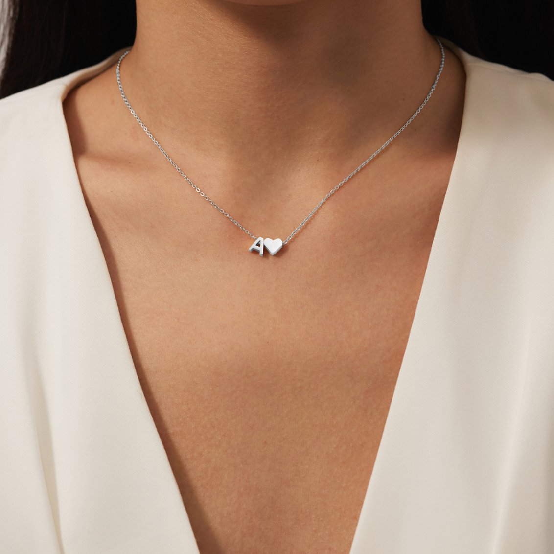 Forever Love & Letter Silver Necklace, worn on a neck with a white V-neck top, letter A and