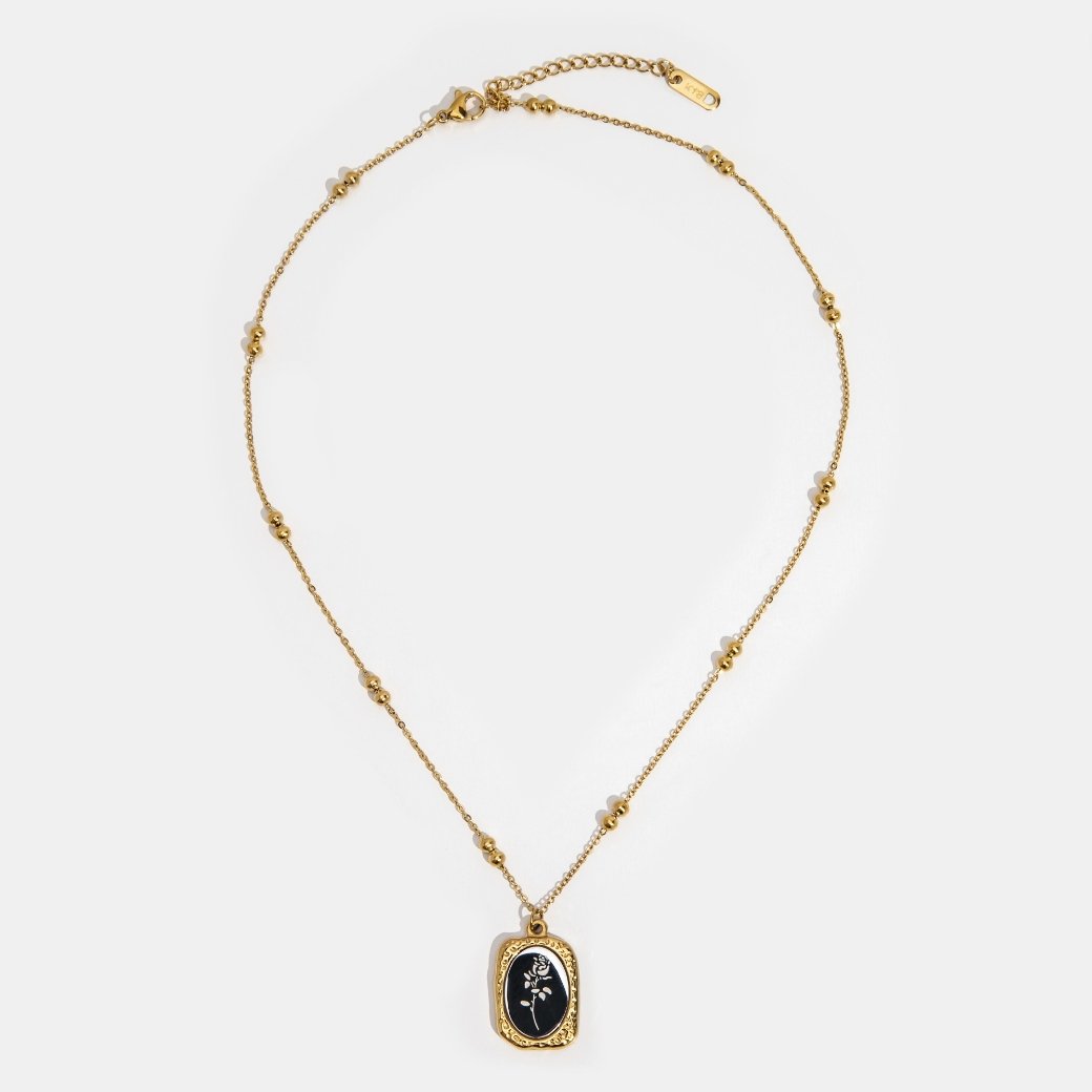 'Fragile Love' Rose Necklace, flat lay of gold bead chain with black pendant bearing a white rose