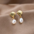 Freshwater Pearl & Gold Shell Earrings, a pair of earrings laid on draped beige satin, close-up