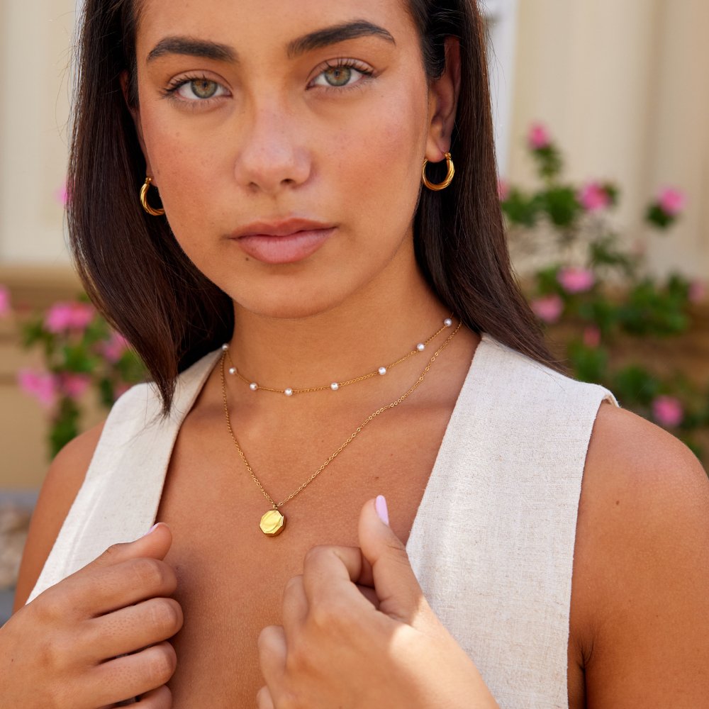 Geometric Pendant Necklace, worn on a model with gold hoop earrings and layered necklaces