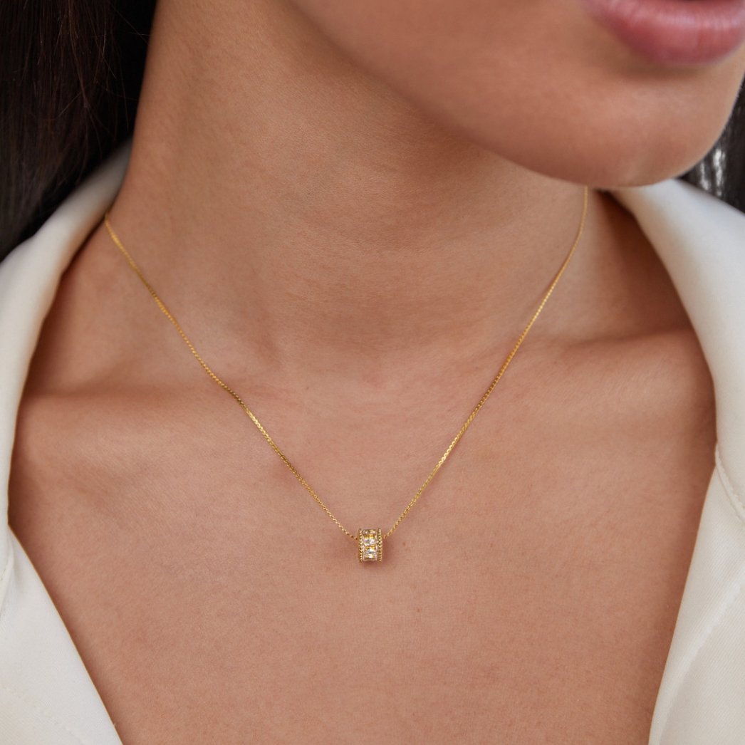 Gigi 18K Gold Set, worn on a neck with a white collared top, close-up on the pendant