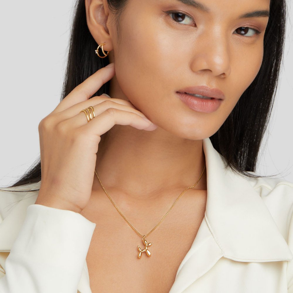 Gold Balloon Animal Necklace, worn on a model with a gold hoop earring and stacked ring