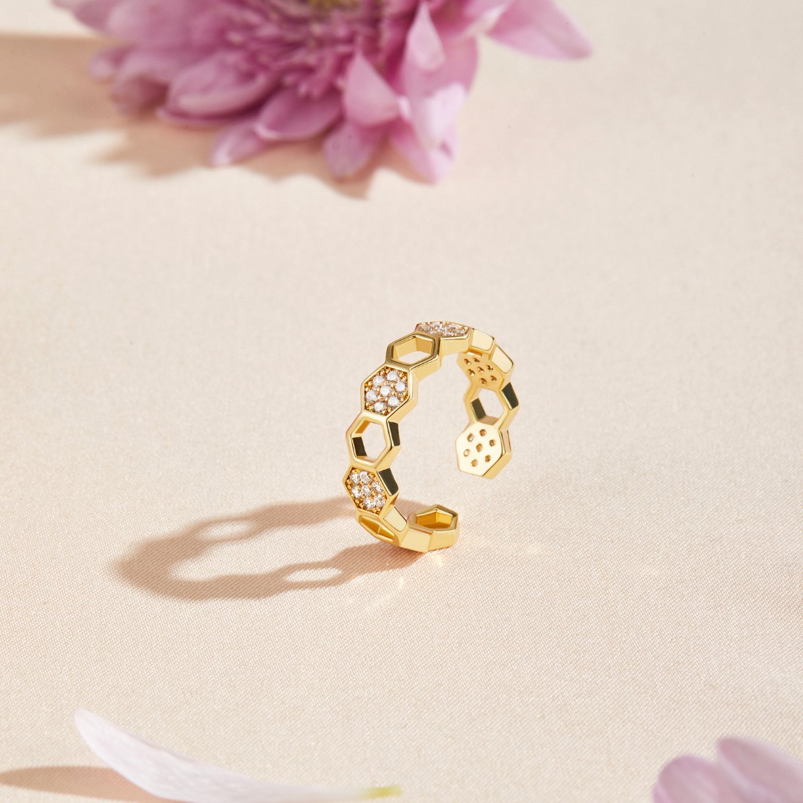 Gold & Crystal Honeycomb Ring, open gold ring with hexagon cells, some set with small stones, on a pale surface
