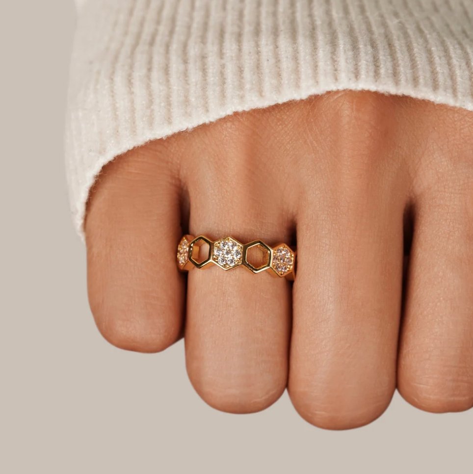 Gold & Crystal Honeycomb Ring, worn on a hand in a cream knit sleeve, close-up on the middle finger