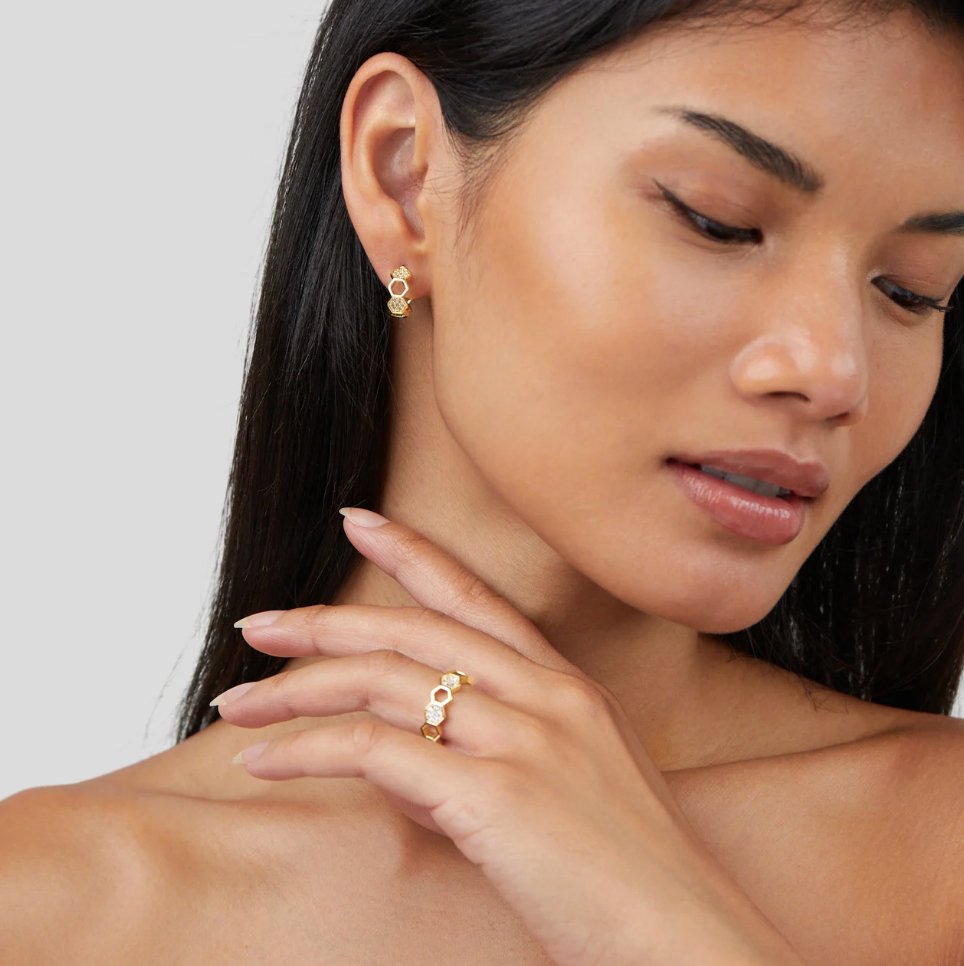 Gold & Crystal Honeycomb Ring, worn on a hand against the neck, with matching gold earring