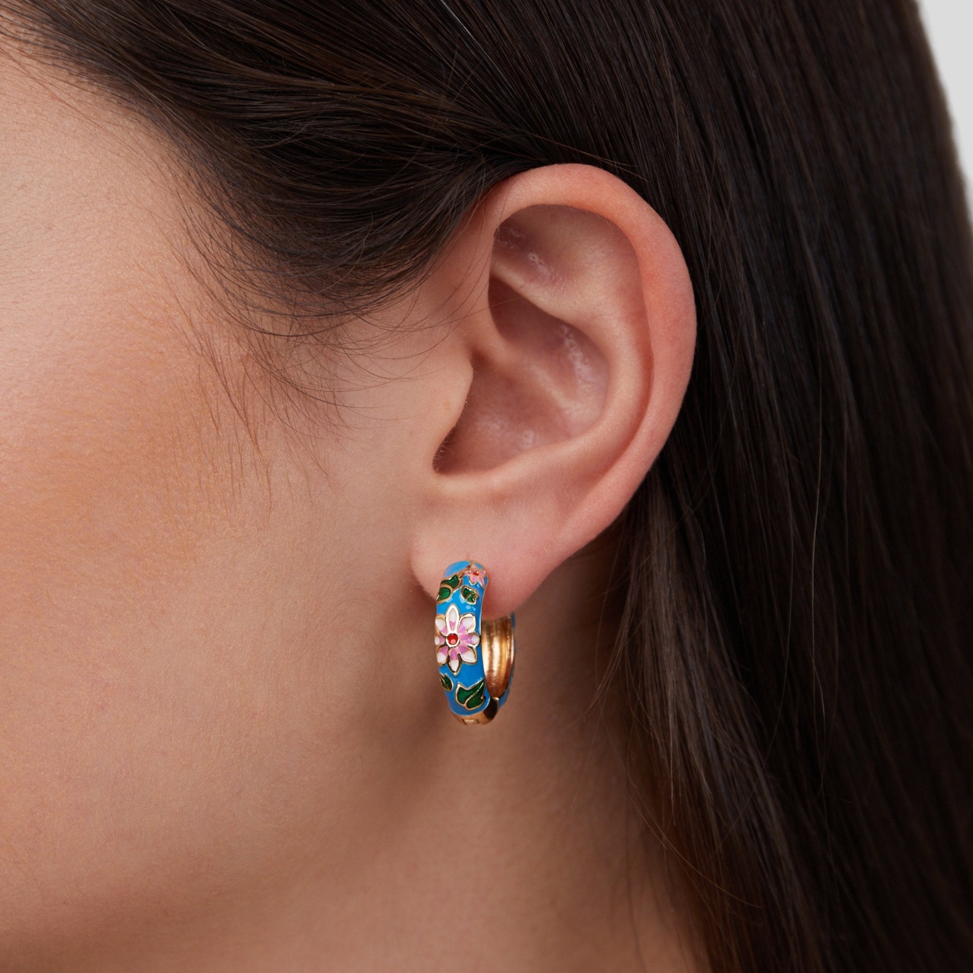 Gold Hoop Flower Earrings, worn on an ear, blue enamel with pink flowers and gold rim