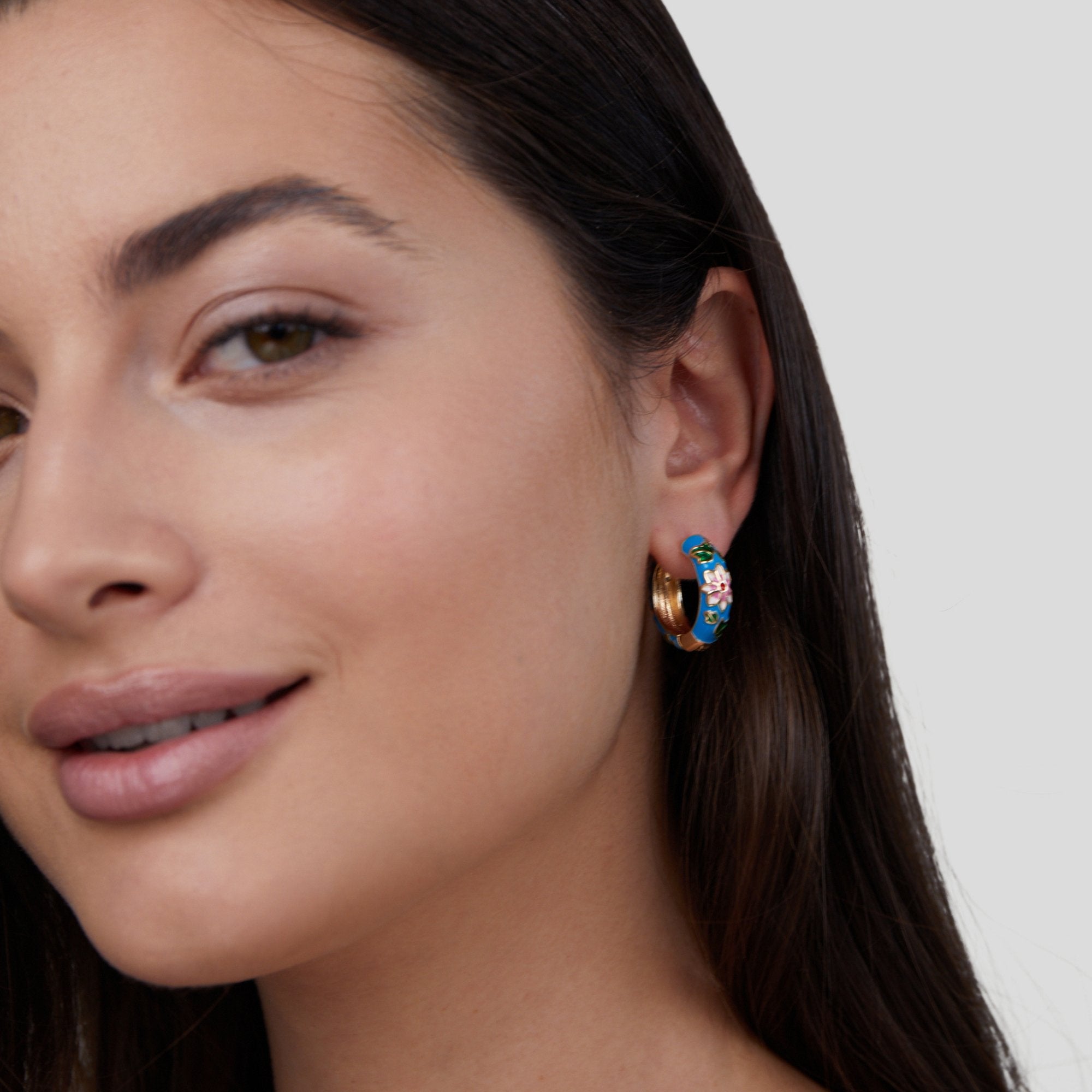 Gold Hoop Flower Earrings, worn on an ear, blue enamel hoop with a pink flower detail