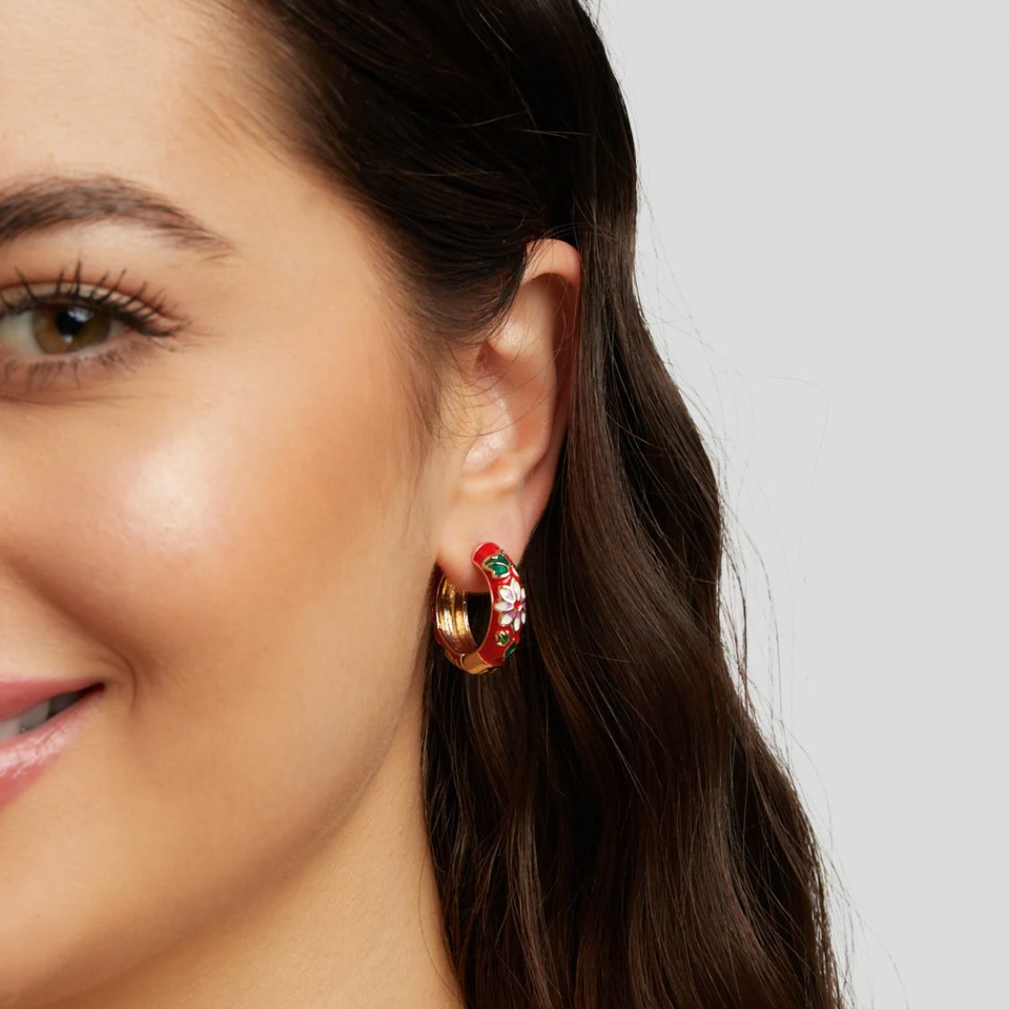 Gold Hoop Flower Earrings, worn on an ear, red enamel with white and green flower motifs