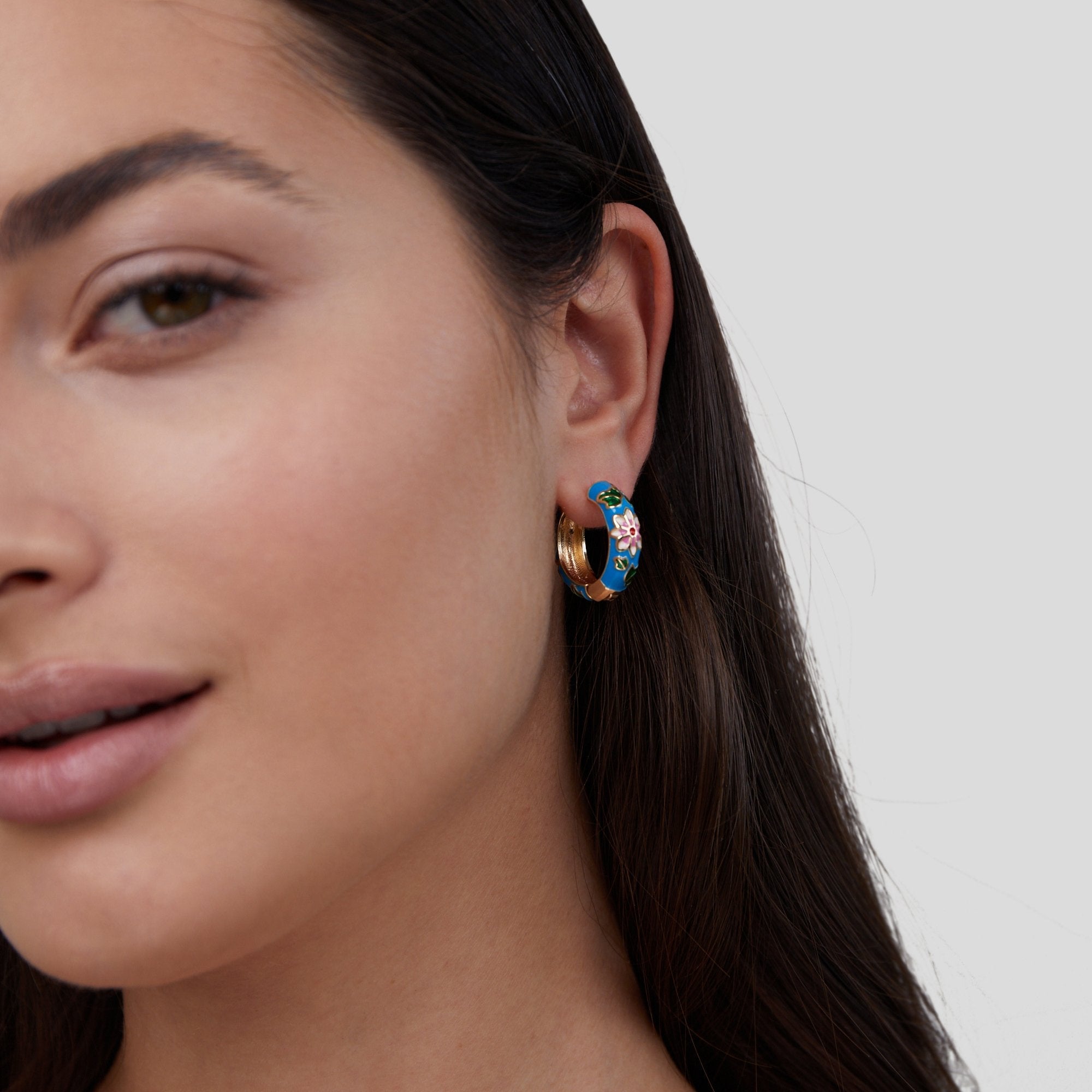 Gold Hoop Flower Earrings, worn on an ear, blue enamel with pink flower and gold edge