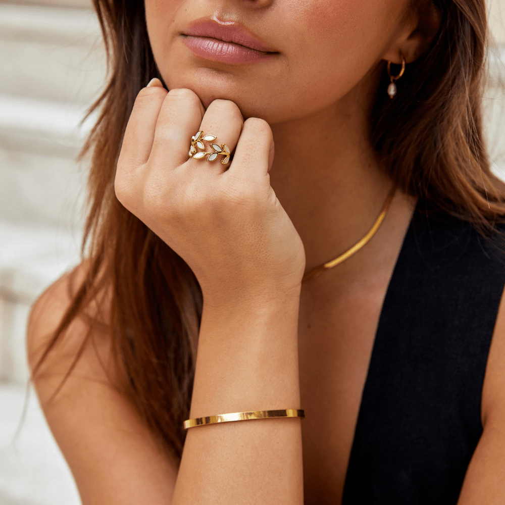 Gold Leaf Ring, worn on a hand under a chin, with a gold cuff and necklace