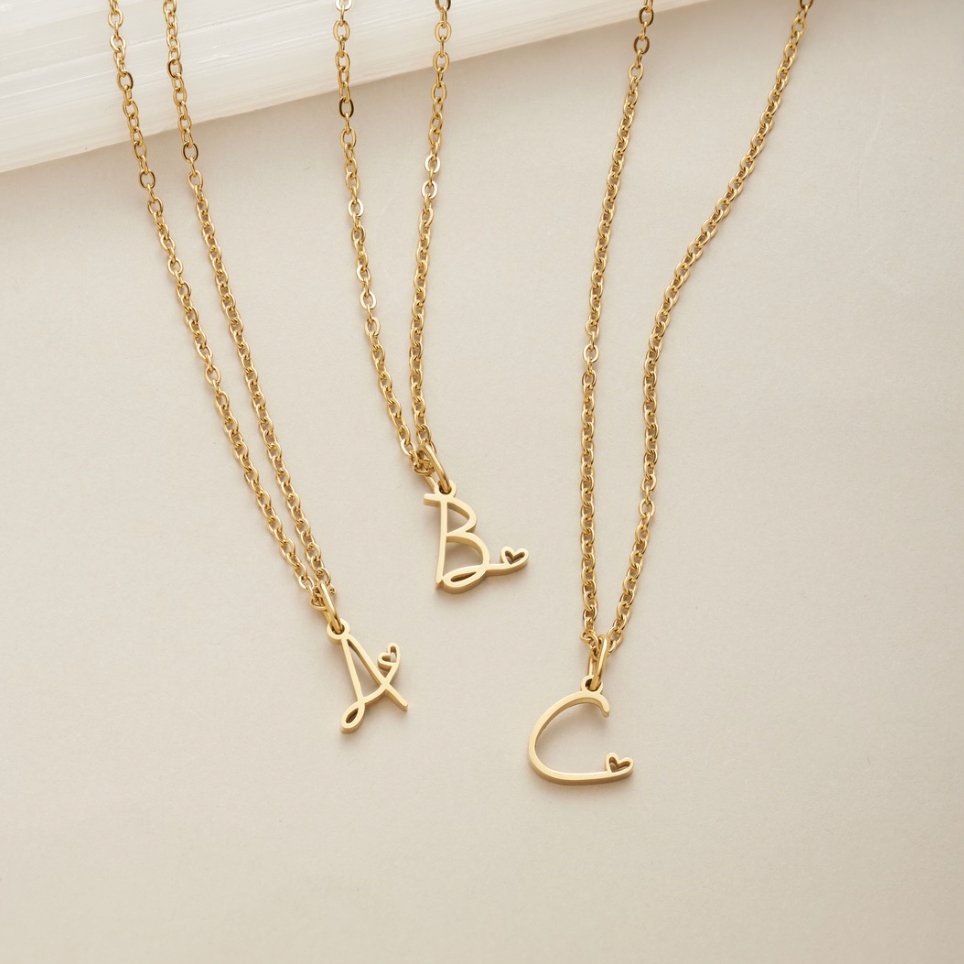 Gold Letter Heart Necklace, three gold chain necklaces laid flat with letter pendants A, B and C